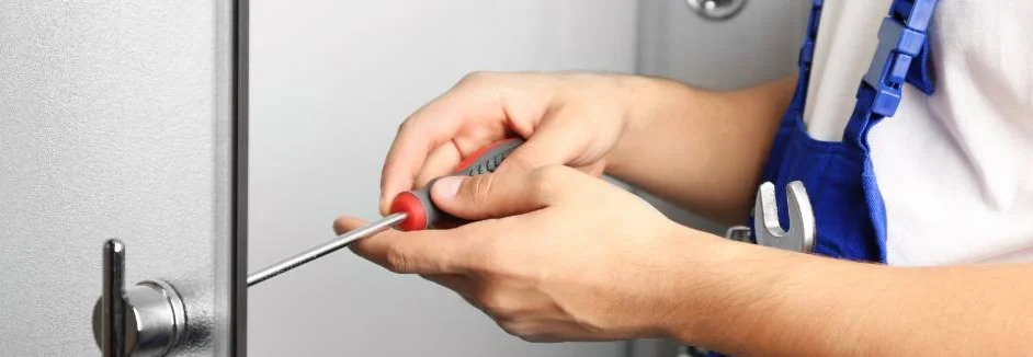 Person repariert Türschloss mit Schraubenzieher.